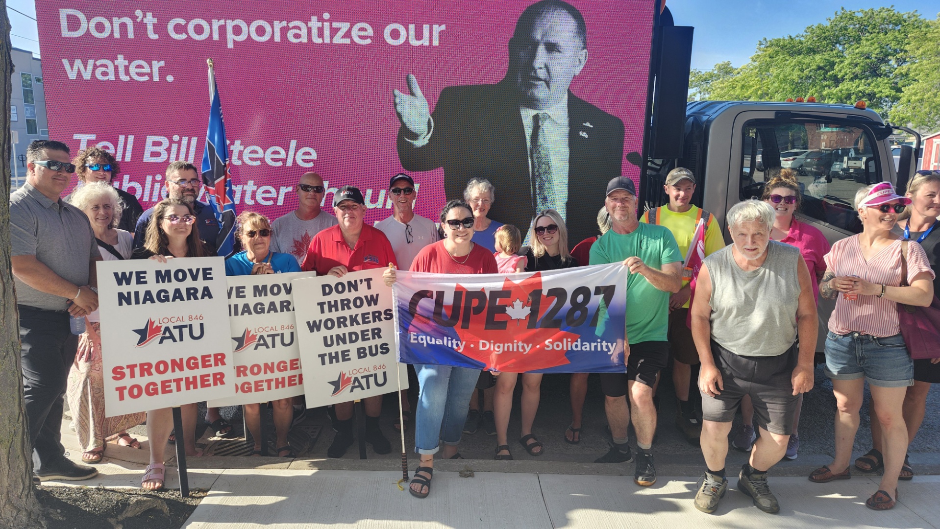 Workes and citizens against privatizing water hold placards against a panel van